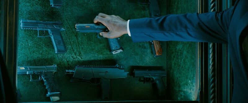Charon reaching for a 2011 pistol in John Wick 3
